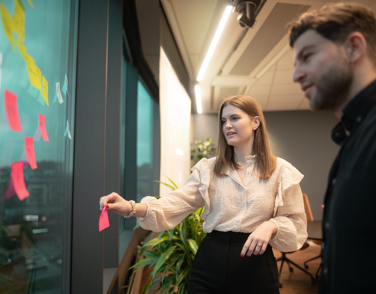 Bilde av mann og dame som henger opp postit lapper på et vindu