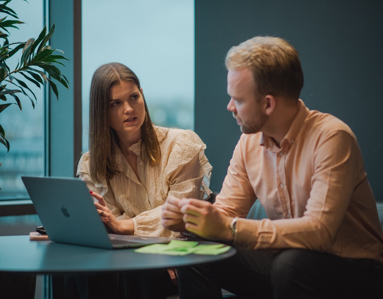 Mann og dame sitter og diskuterer foran en PC