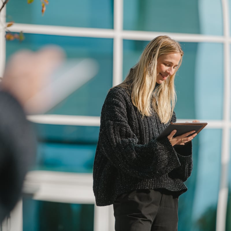 Bilde av en dame som ser ned og holder en ipad